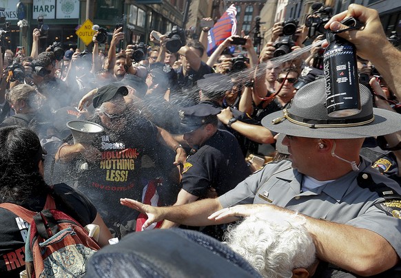 A law enforcement officer tries extinguish a burning American flag, Wednesday, July 20, 2016, in Cleveland, during the third day of the Republican convention. (AP Photo/Alex Brandon)