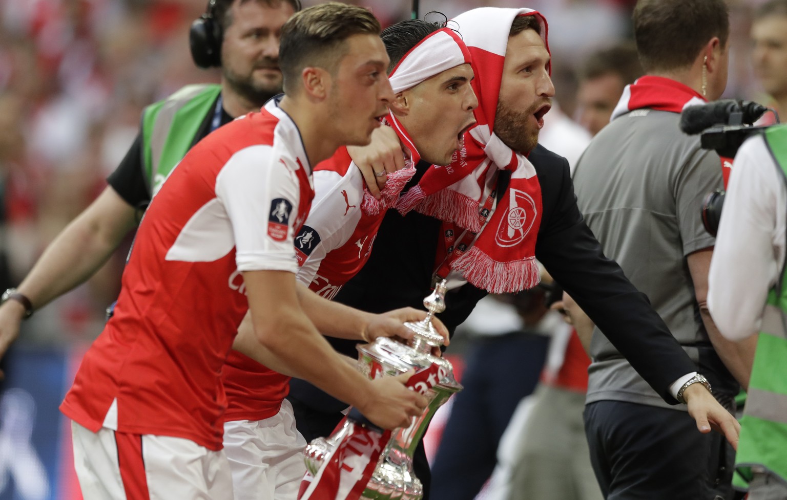 From left, Arsenal&#039;s Mesut Ozil, Granit Xhaka and Shkodran Mustafi celebrate with the trophy after winning the English FA Cup final soccer match between Arsenal and Chelsea at the Wembley stadium ...