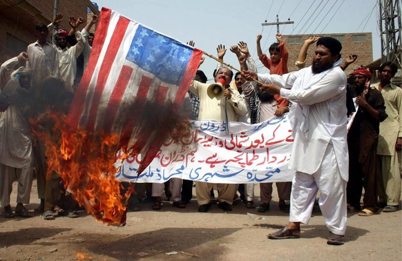 Menschen verbrennen eine nachgemachte US-Flagge, während sie bei einem Protest gegen US-Drohnenangriffe in Multan, Pakistan, am 07. Juli 2012 Parolen rufen. Mindestens 20 Menschen wurden bei einem US- ...