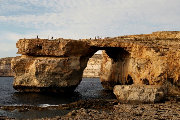 FILE PHOTO: Tourists walk on the Azure Window, a 50 metre high rock arch, at Dwejra Point cliffs on the west coast of the Maltese island of Gozo September 23, 2016. REUTERS/Darrin Zammit Lupi/File pho ...