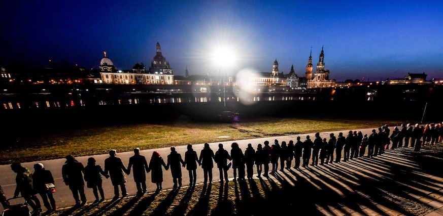 epa05791470 People join hands to form a human chain along the Elbe river opposite of the Dresden skyline to commemorate the destruction of the city during World War II, in Dresden, Germany, 13 Februar ...