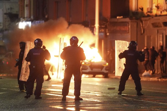 A car burns as Irish policemen stand at the scene of an attack in Dublin city centre, Thursday Nov. 23, 2023. A 5-year-old girl is receiving emergency medical treatment in a Dublin hospital following  ...