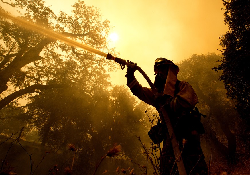 Napa County firefighter Jason Sheumann sprays water on a home as he battles flames from a wildfire Monday, Oct. 9, 2017, in Napa, Calif. More wastewater has been discharged into the Niagara River in t ...