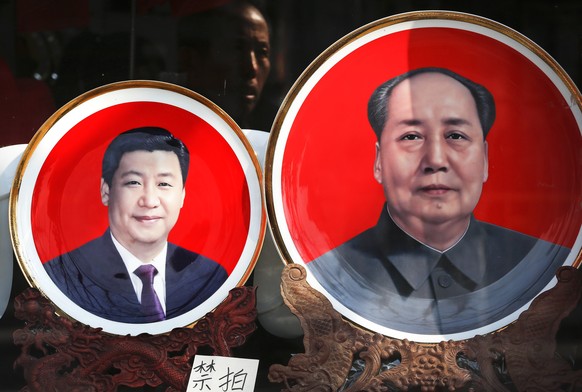 In this Tuesday, March 1, 2016 photo, a man looks at souvenir plates bearing images of Chinese President Xi Jinping, left, and late Chinese leader Mao Zedong on display at a shop near Tiananmen Square ...