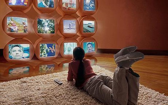 Girl (10-12) lying on floor, watching different TV screens