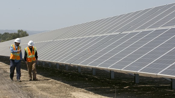 FILE - In this Aug. 17, 2017, file photo, solar tech Joshua Valdez, left, and senior plant managerTim Wisdom walk past solar panels at a Pacific Gas and Electric Solar Plant, in Dixon, Calif. Cheap so ...