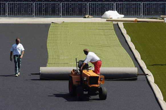 Arbeiter aus Deutschland verlegen die ersten Bahnen Kunstrasen am Montag, 12. Juni 2006 im Stade de Suisse Wankdorf in Bern. (KEYSTONE/ Lukas Lehmann)