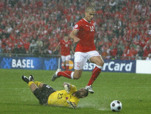 Swiss Eren Derdiyok (R) passes the ball past Turkish goalie Volkan Demirel (on ground) during the EURO 2008 preliminary round group A match between Switzerland and Turkey at the St. Jakob Park stadium ...