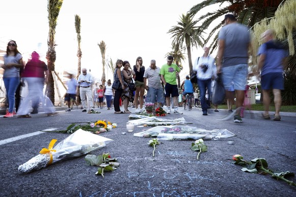 epa05428412 People put flowers and write words on the ground next to traces of blood and pay their respects on the &#039;Promenade des Anglais&#039; where the truck crashed into the crowd during the B ...