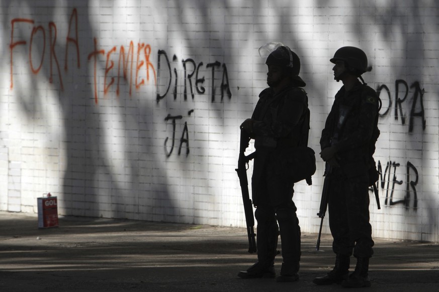 Soldiers stand guard outside a federal building where graffiti says in Portuguese &quot;Get out Temer&quot; and &quot;Direct elections now&quot; in Brasilia, Brazil, Thursday, May 25, 2017. Brazil&#03 ...