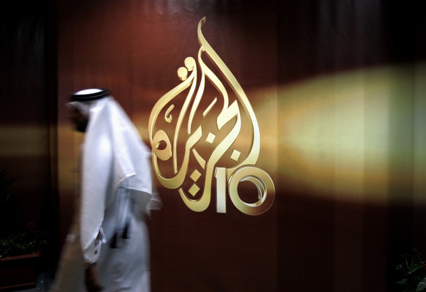 FILE -- In this Nov. 1, 2006 file photo, a Qatari employee of Al Jazeera Arabic language TV news channel walks past the logo of Al Jazeera in Doha, Qatar. Hackers allegedly broke into the website of Q ...