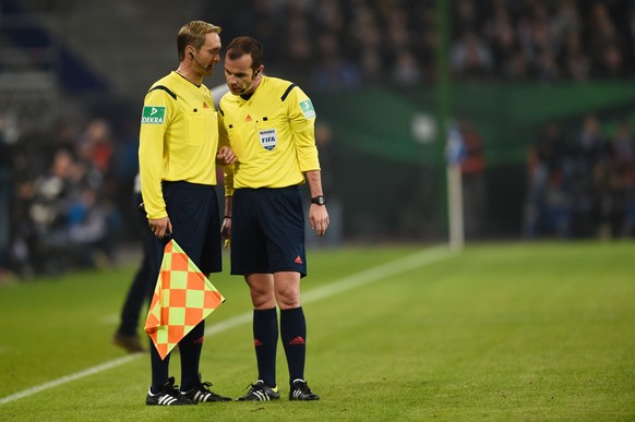 A linesman informs referee Marco Fritz (R) that Bayern Munich&#039;s midfielder Thomas Mueller&#039;s was offside and so the goal was disallowed during the German Cup DFB football match FC St Pauli vs ...