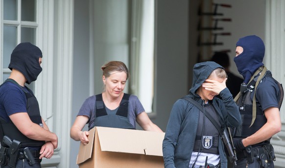 epa06082592 Special Police Officers watch the door while a colleague carries a box from a house during a raid in the &#039;Neukoelln&#039; district of Berlin, Germany, 12 July 2017. In connection with ...