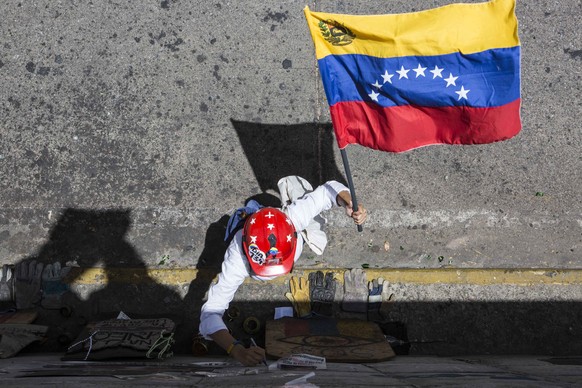 epa06141355 A woman waves a Venezuelan flag during an opposition protest against the Government in Caracas, Venezuela, 12 August 2017. Dozens of Venezuelans marched from different municipalities of th ...