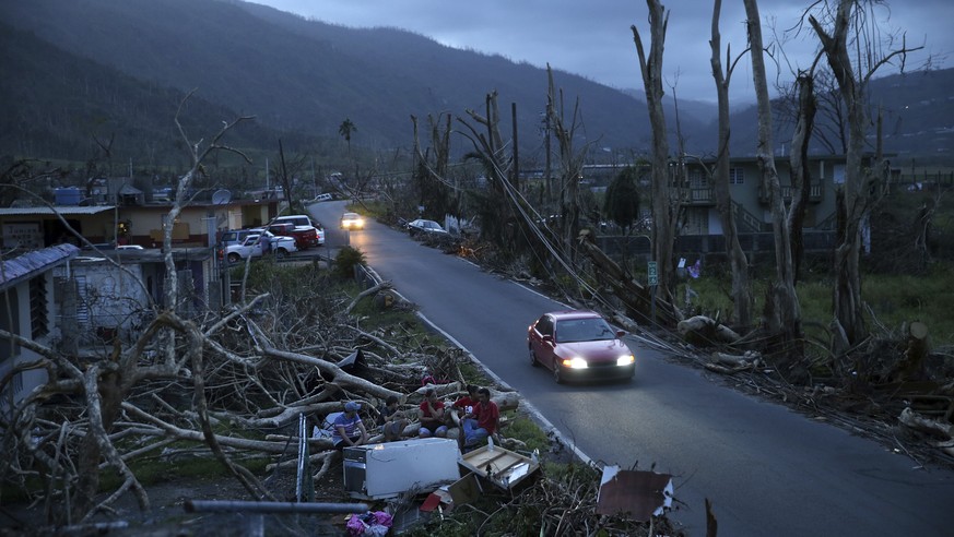 FILE - In this Sept. 26, 2017 file photo, neighbors sit on a couch outside their destroyed homes as the sun sets in the aftermath of Hurricane Maria, in Yabucoa, Puerto Rico. The strongest hurricane t ...