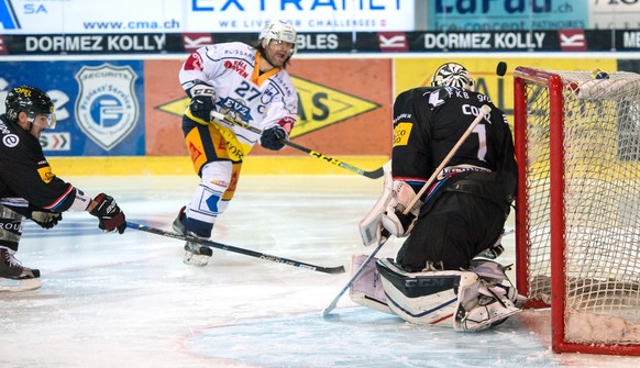 Le joueur zougois Josh Holden, gauche, lutte pour le puck avec le gardien fribourgeois Benjamin Conz, droite, lors de la rencontre du championnat suisse de hockey sur glace de National League, LNA, en ...