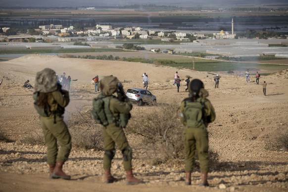 FILE -- In this Nov. 17, 2016 file photo, Palestinians and Israeli activists run away from a tear gas fired by Israeli soldiers during a demonstration against the construction of Jewish settlements in ...