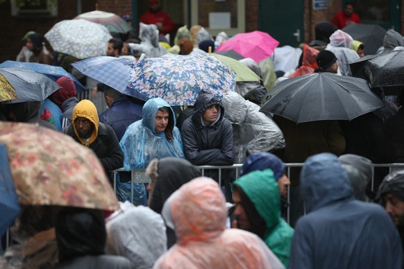 BERLIN, GERMANY - OCTOBER 08: Migrants wait under rain and cold weather outside the Central Registration Office for Asylum Seekers (Zentrale Aufnahmestelle fuer Asylbewerber, or ZAA) of the State Offi ...