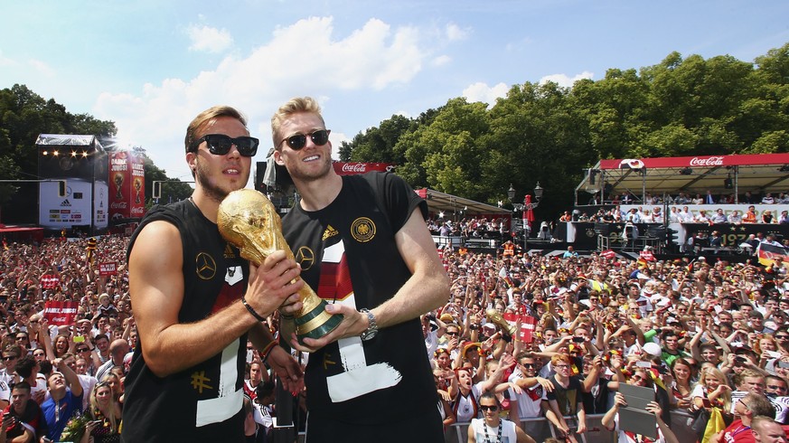 Germany&#039;s Mario Goetze (L) and Andre Schuerrle pose with the World Cup trophy during celebrations to mark the team&#039;s 2014 Brazil World Cup victory, at a &#039;fan mile&#039; public viewing z ...