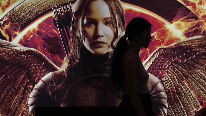 A woman is silhouetted against a billboard of the movie “The Hunger Games: Mockingjay - Part 1” in Bangkok, Thailand, Thursday, Nov. 20, 2014. Police detained three students Thursday at the opening of ...