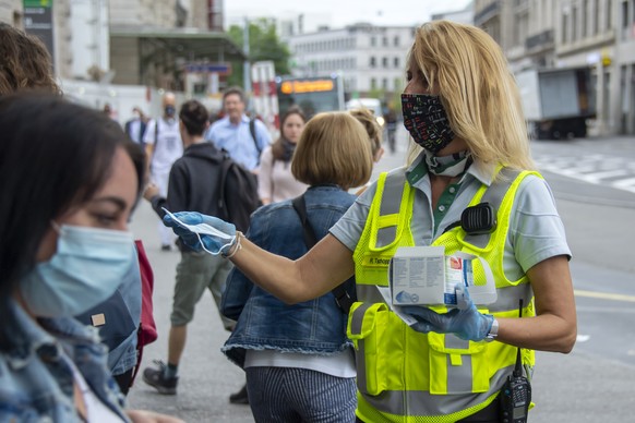 Eine Mitarbeiterin der Basler Verkehrs-Betriebe BVB verteilt Schutzmasken am Bahnhof SBB in Basel, am Montag, 6. Juli 2020. Das Schutzkonzept gegen das Coronavirus wurde angepasst: Alle Reisenden mues ...