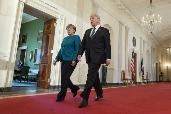 epa05854905 US President Donald J. Trump (R) and Chancellor of Germany Angela Merkel (L) walk down the Cross Hall to enter the East Room for a joint press conference in the East Room of the White Hous ...