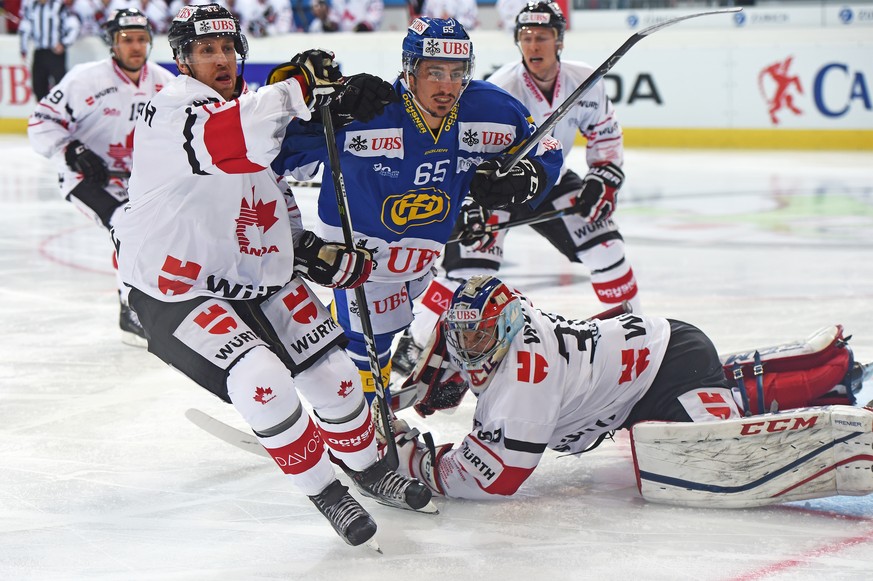 Davos Marc Wieser, middle, fights for the puck against Canadas Shaone Morrisonn and goalkeeper Zach Fucale, during the game between Switzerlands HC Davos and Team Canada at the 90th Spengler Cup ice h ...