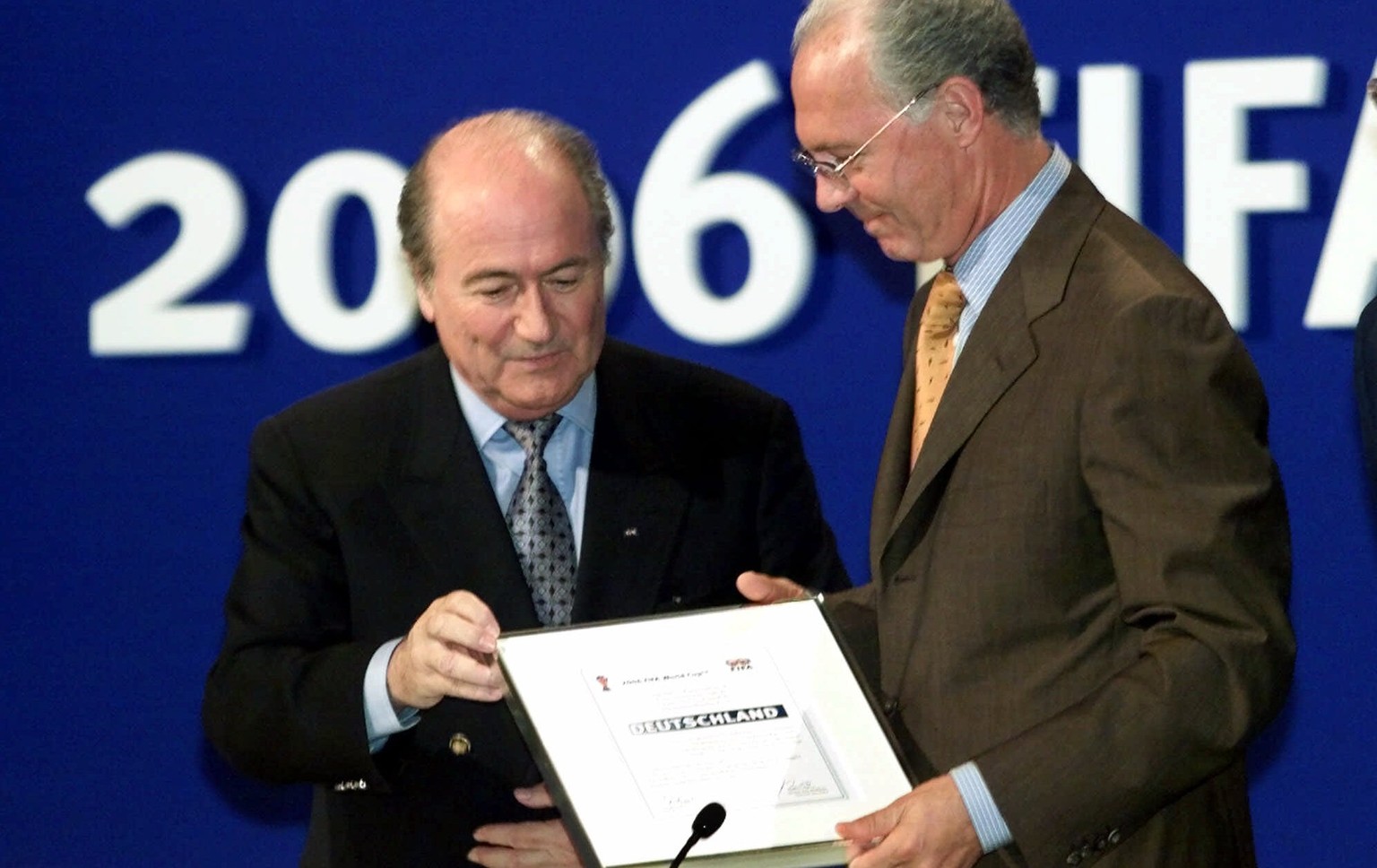 Blatter übergibt Beckenbauer die Bestätigung für den WM-Zuschlag 2006.