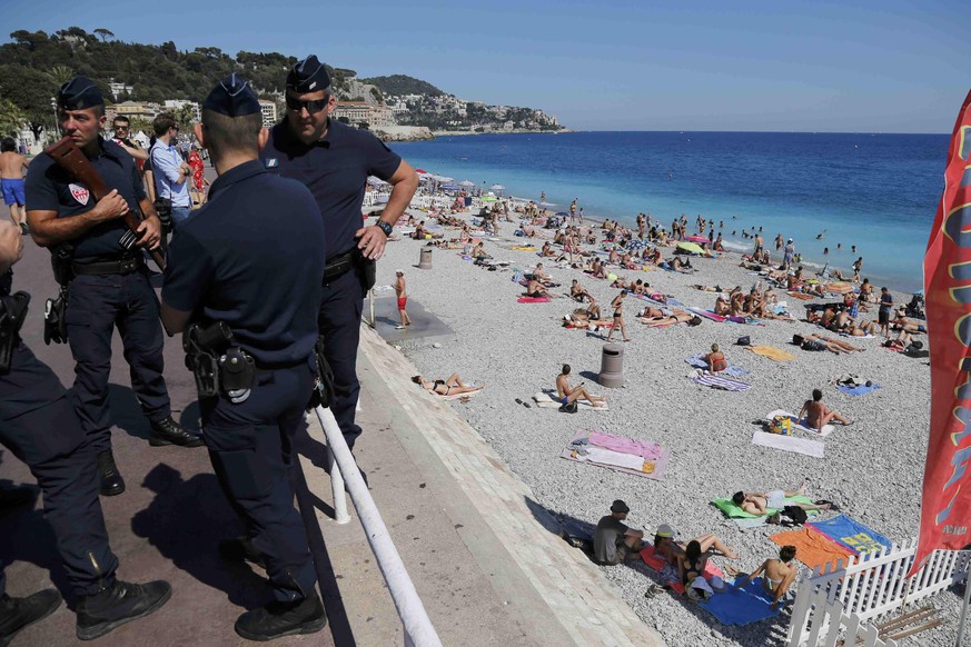 French CRS police patrol on the walkway above a public beach with sunbathers as security measures continue after the Bastille Day truck attack by a driver who ran into a crowd on the Promenade des Ang ...