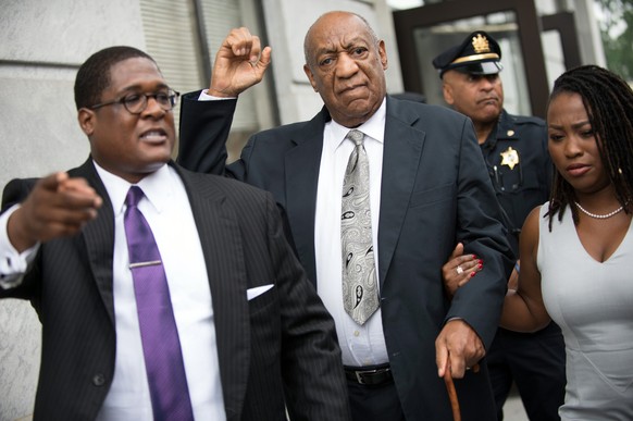 epa06033491 US entertainer Bill Cosby (C) raise his fist as he leaves with his spokesperson Andrew Wyatt (L) the Montgomery County Courthouse in Norristown, Pennsylvania, USA, 17 June 2017, after a mi ...