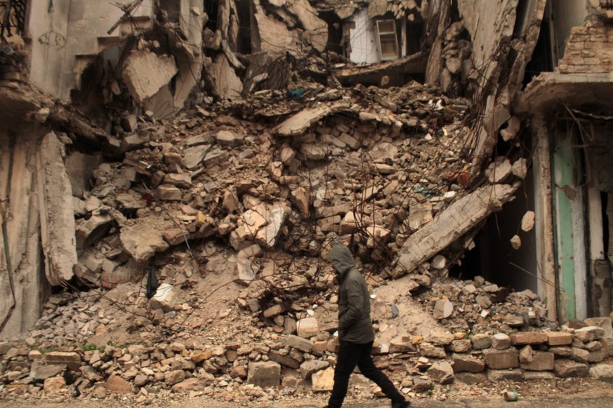 epa05675594 A man walks next to a destroyed building one day after a ceasefire was announced, at al-Mashhad neighborhood in the rebel-held part of Aleppo, Syria, 14 December 2016. Syrian Observatory f ...