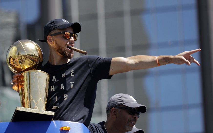 FILE - In this June 15, 2017, file photo, Golden State Warriors&#039; Stephen Curry gestures while holding the Larry O&#039;Brien trophy during a parade and rally after winning the NBA basketball cham ...