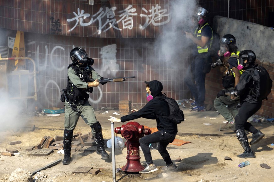 A policeman in riot gear points his weapon as protesters try to flee from the Hong Kong Polytechnic University in Hong Kong, Monday, Nov. 18, 2019. Hong Kong police have swooped in with tear gas and b ...
