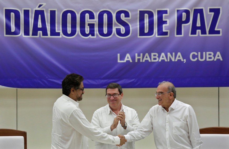 Colombia&#039;s FARC lead negotiator Ivan Marquez (L) and Colombia&#039;s lead government negotiator Humberto de la Calle (R) shake hands while Cuba&#039;s Foreign Minister Bruno Rodriguez looks on, a ...