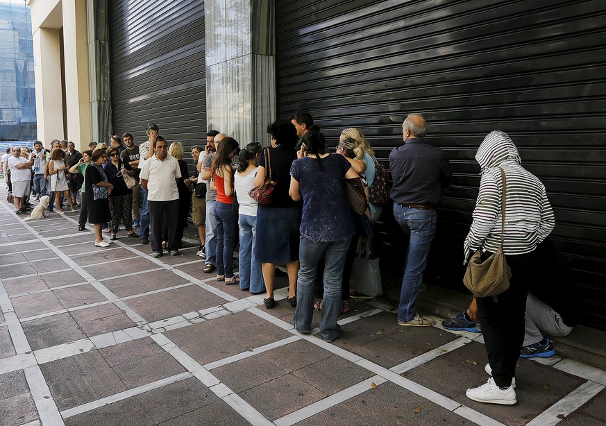 Menschen warten vor einer geschlossenen Bankfiliale in Athen.