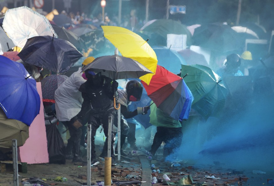 Protestors react as blue-dyed liquid is sprayed from an armored police vehicle at Hong Kong Polytechnic University in Hong Kong, Sunday, Nov. 17, 2019. A Hong Kong police officer was hit in the leg by ...