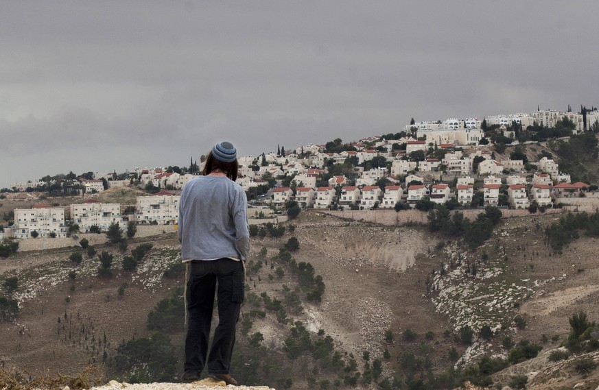 FILE - in this Wednesday, Dec. 5, 2012 file photo, A Jewish settler looks at the West bank settlement of Maaleh Adumim, from the E-1 area on the eastern outskirts of Jerusalem. In his landmark speech  ...