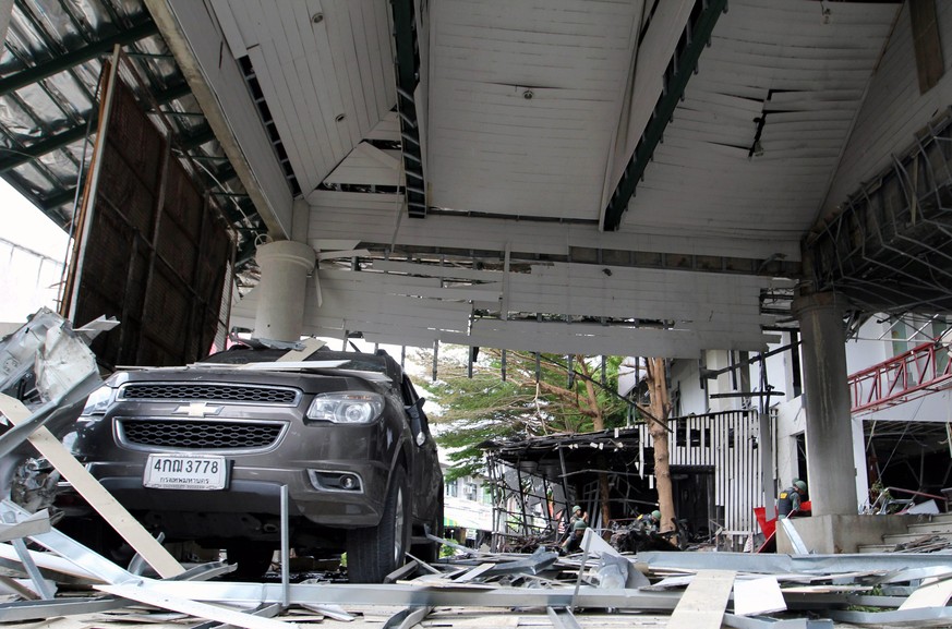 epa05508103 Members of the Thai Explosive Ordnance Disposal (in background) unit inspect a bomb blast scene after a car bomb attack at a hotel in Pattani, southern Thailand, 24 August 2016. A series o ...