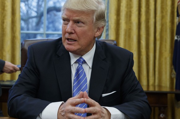 FILE - In this Jan. 23, 2017 file photo, President Donald Trump sits at his desk in the Oval Office of the White House in Washington. The legal fight over President Donald Trump’s refugee ban is likel ...