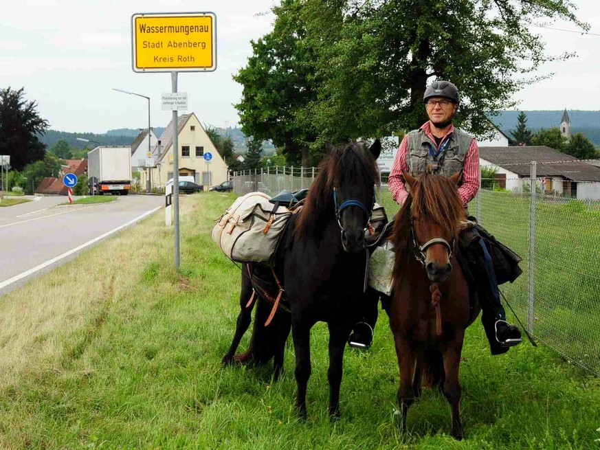 Hans Watzl sitzt am 05.09.2017 am Ortsschild von Wassermungenau (Bayern) auf seinem Pferd Solfari, daneben steht Flüga. Weil er seinem Enkel versprochen hat, ihn mit dem Pferd von der Schule abzuholen ...