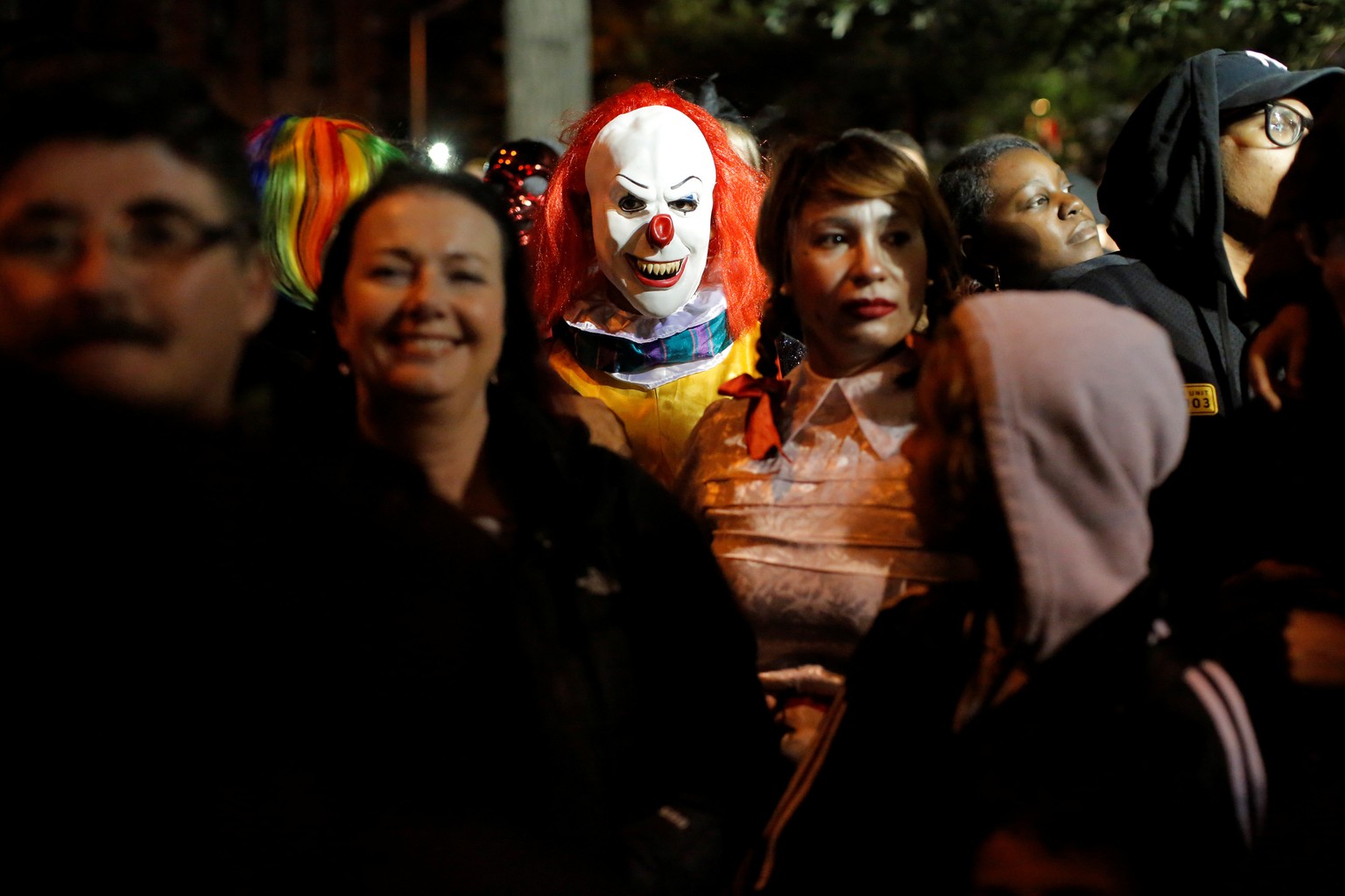 A person dressed in a clown costume stands amongst attendees during the Greenwich Village Halloween Parade in Manhattan, New York, U.S., October 31, 2016. REUTERS/Andrew Kelly