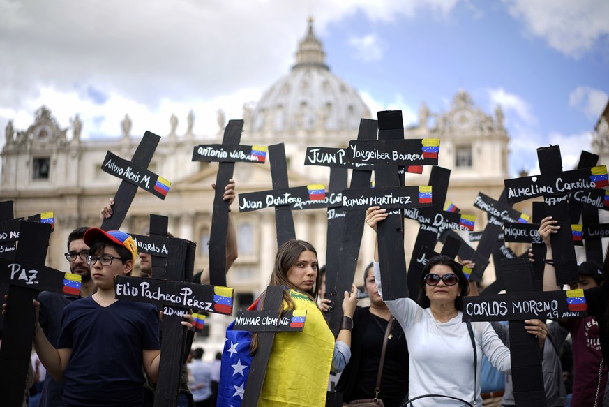 Demonstrators hold black crosses adorned with Venezuela flags and with the names of those who were killed in weeks of violent demonstrations calling on Venezuela&#039;s President Nicolas Maduro to ste ...