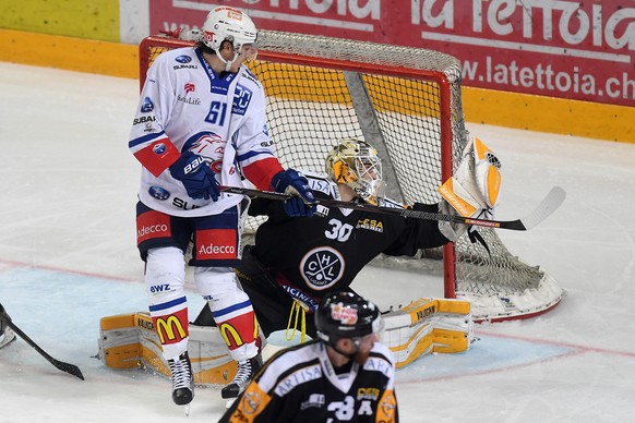 Zurich&#039;s player Fabrice Herzog, left, fights for the puck with Lugano’s goalkeeper Elvis Merzlikins, right, during the sixth leg of the Playoffs quarterfinals game of National League A (NLA) Swis ...