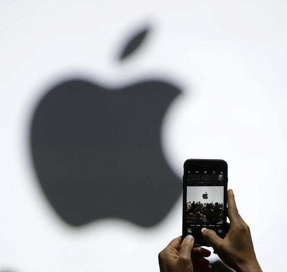 FILE - In this Monday, June 5, 2017, file photo, a person takes a photo of an Apple logo before an announcement of new products at the Apple Worldwide Developers Conference in San Jose, Calif. Apple i ...