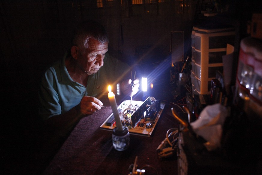 Stromausfall in San Cristobal, Venezuela: Ein Mann repariert ein Gerät bei Kerzenlicht.&nbsp;