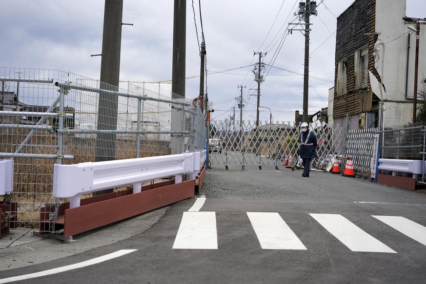 epa09053318 A security guard stands at a gate near Yonomori station in Tomioka, Fukushima prefecture, Japan, 17 February 2021 (issued 05 March 2021). More than 36,000 people who evacuated Fukushima af ...