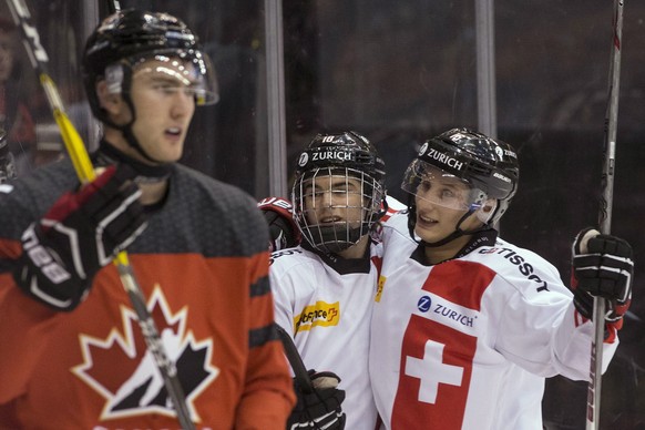 Switzerland&#039;s Nico Hischier, center, celebrates with Loic In-Albon after scoring against Canada during the second period of an exhibition game ahead of the IIHF World Junior hockey championships, ...