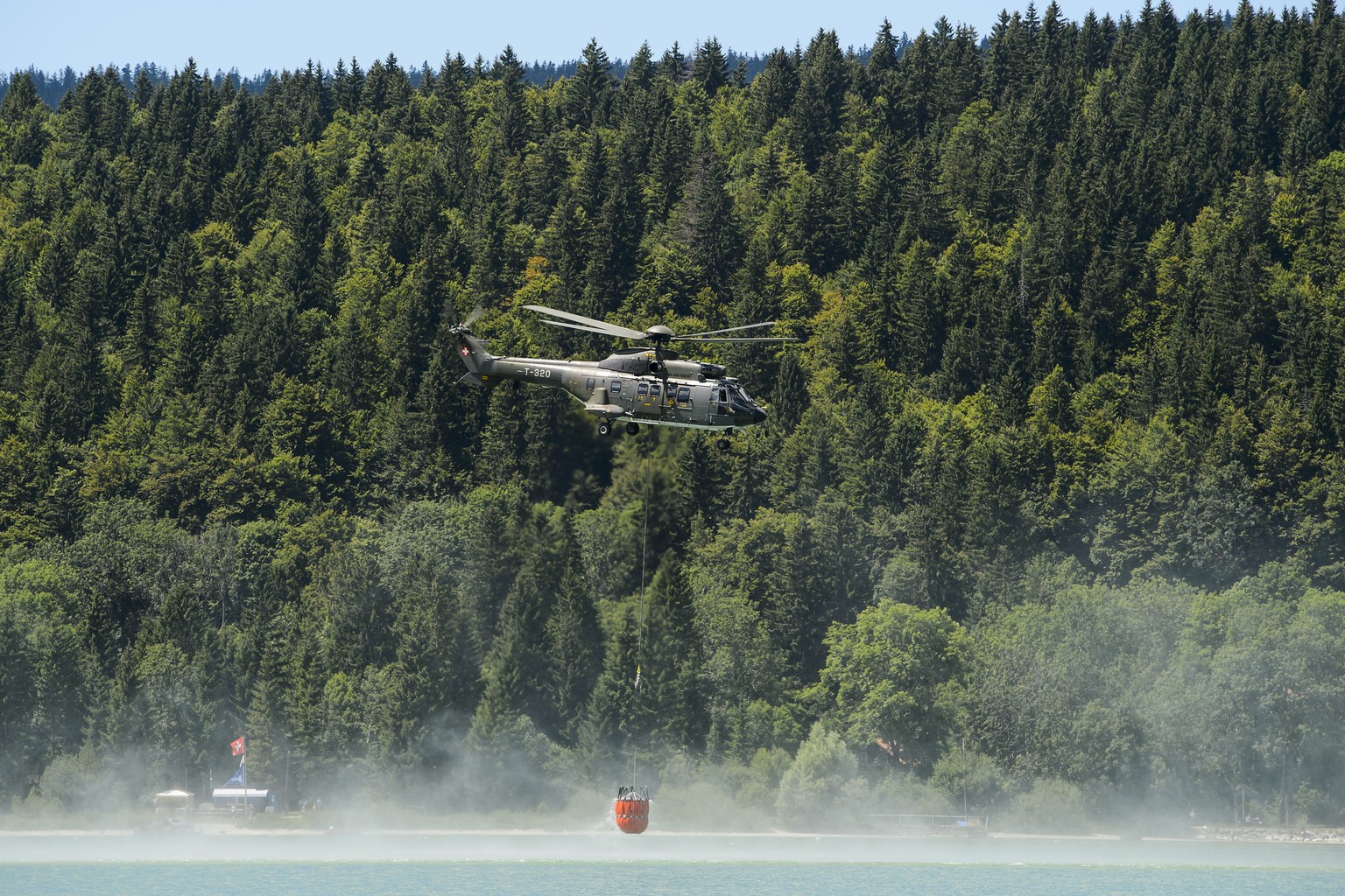 Ein Superpuma schöpft Wasser aus dem Lac de Joux.