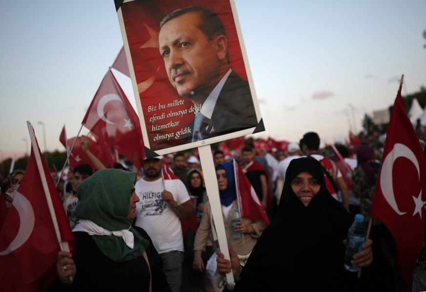 A woman holds placard depicting Turkish president Erdogan during &quot;National Unity March&quot; to commemorate the one year anniversary of the July 15, 2016 botched coup attempt, in Istanbul, Saturd ...