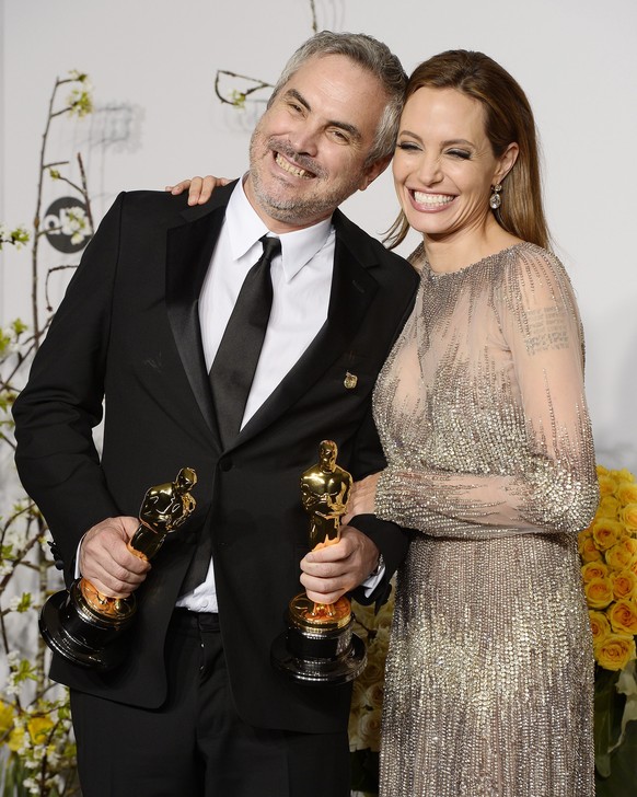 epa04107347 Mexican director Alfonso Cuaron (L) holds his Oscars for Best Achievement in Directing and Best Achievement in Film Editing for &#039;Gravity&#039; as he stands with US actress Angelina Jo ...